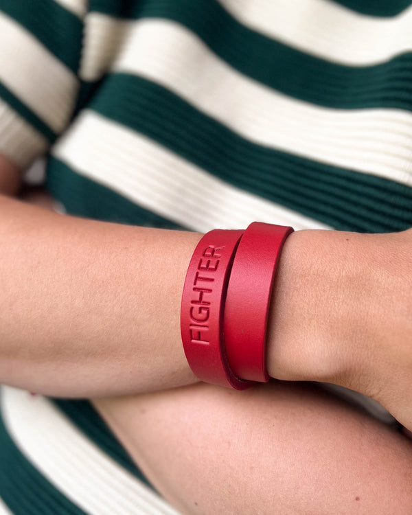 DUO Lederarmband in Rot mit der Gravur "Fighter" doppelt ums Handgelenk gewickelt, grün-weiß gestreifter Pullover
