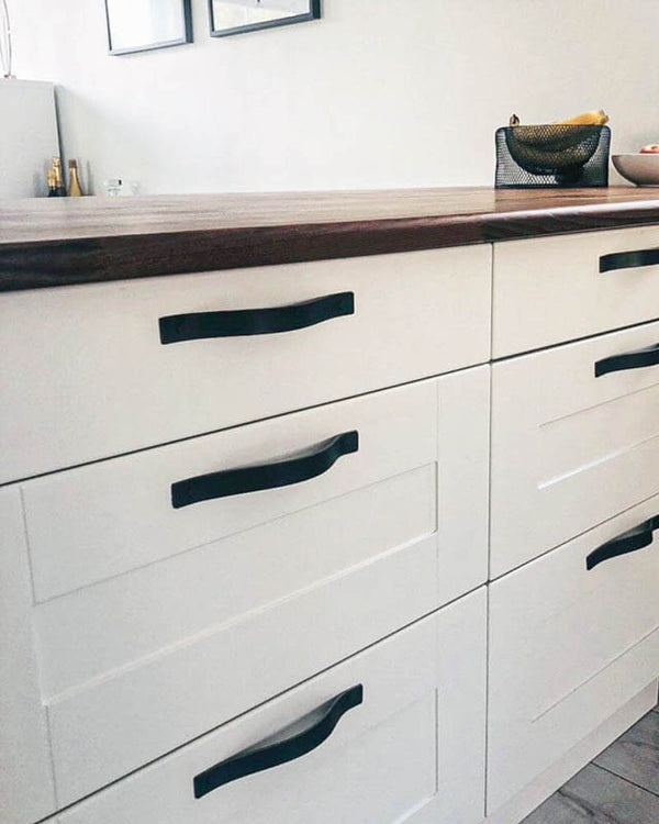 BAND Ledergriffe in Schwarz waagerecht an weißen Küchenschubladen unter Arbeitsplatte aus Nussbaum montiert