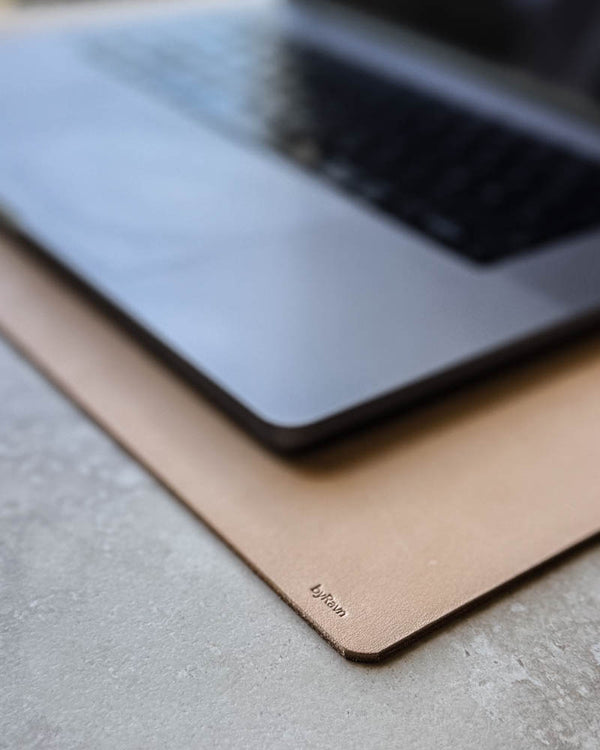 XXL DESK Schreibtischunterlage aus naturfarbenem Leder mit byRavn-Prägung unter Laptop auf heller Tischplatte