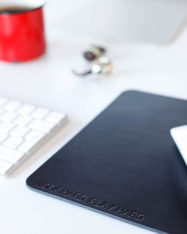 DOS Mauspad aus schwarzem Leder mit der Gravur "Work hard, play hard" auf Schreibtisch mit Tastatur und roter Tasse