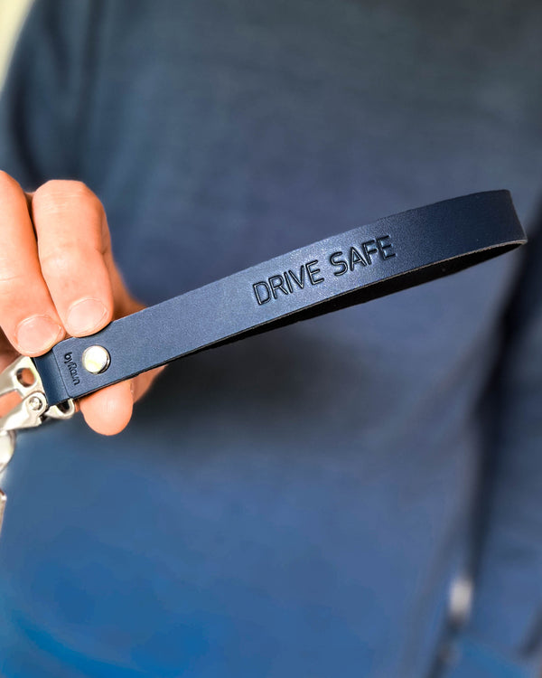 IRON Schlüsselanhänger aus dunkelblauem Leder mit langer Schlaufe und der Gravur "Drive safe", in der Hand gehalten