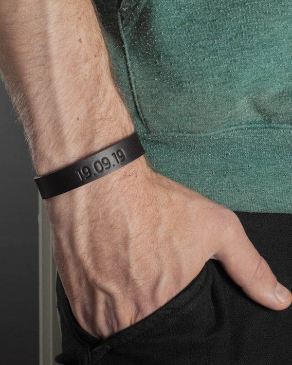 MONO Lederarmband in Dunkelbraun mit graviertem Datum "19.09.19" am Handgelenk eines Mannes, grünes T-Shirt