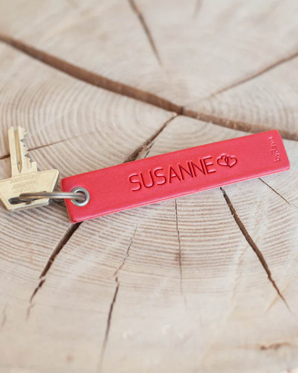 SOLO Medium Schlüsselanhänger aus rotem Leder mit dem gravierten Namen "Susanne" und zwei Herzen, mit Schlüssel auf Holzscheibe