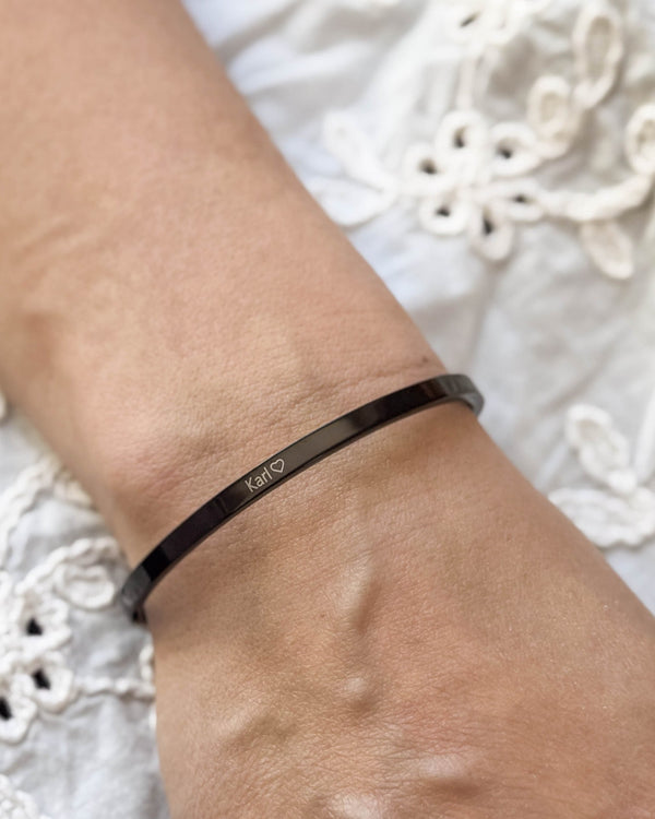 VENUS Armband aus schwarzem Edelstahl mit graviertem Namen "Karl" ♡ am Handgelenk, weiße bestickte Bluse