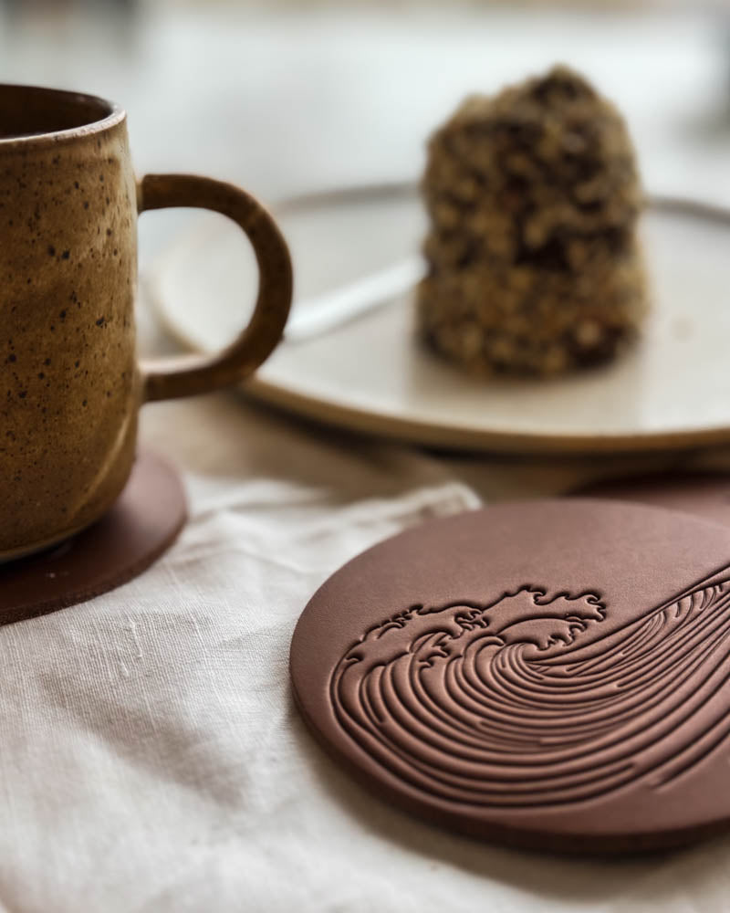 Coasters og ølbrikker i læder – MOKKA rund bordskåner i cognac læder præget med stor bølge ved siden af kaffekop