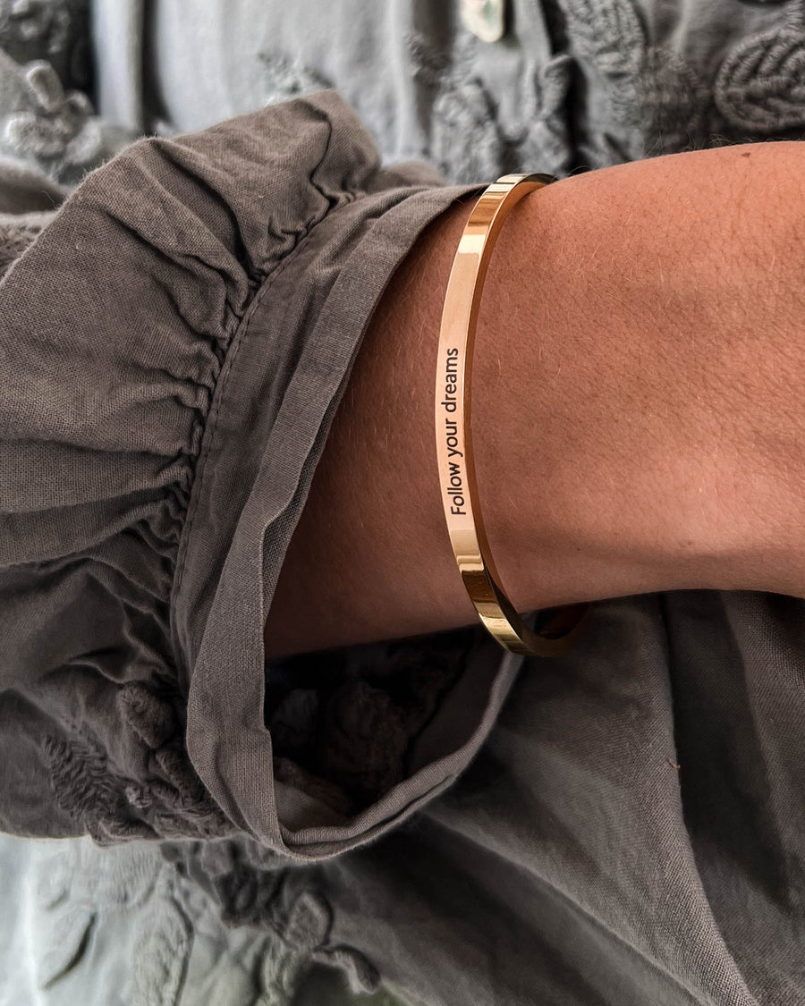 VENUS Armband aus vergoldetem Edelstahl mit der Gravur "Follow your dreams" am Handgelenk getragen