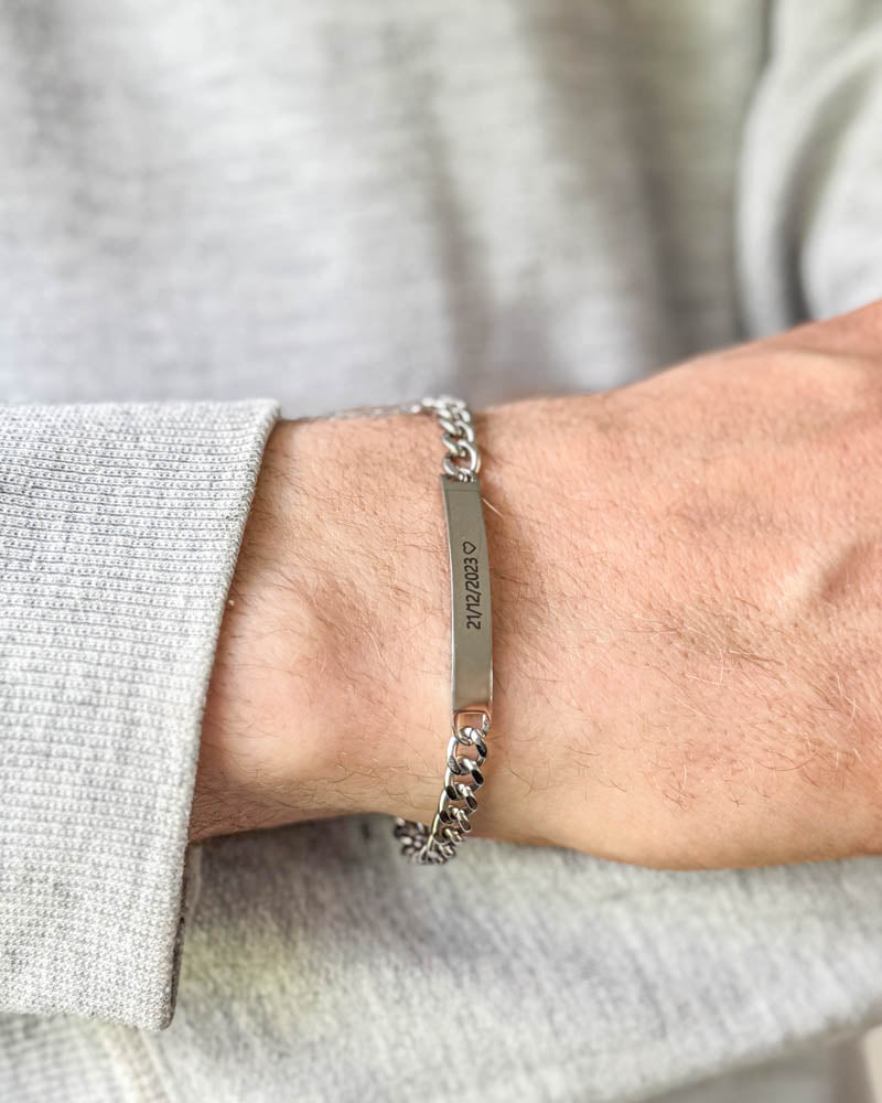 ARA Armband aus silberfarbenem Edelstahl mit dem Datum "21/12/2023" ♡ graviert, am Handgelenk zu hellgrauem Sweatshirt getragen