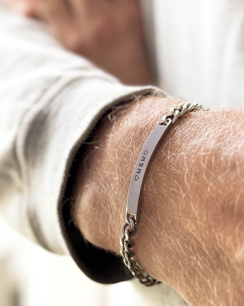 ARA Armband aus silberfarbenem Edelstahl mit den Initialen "♡ M & M ♡" graviert, am Handgelenk, weißes Sweatshirt