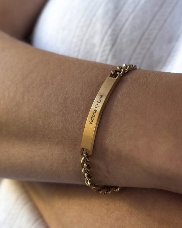 AVA Armband aus gebürstetem vergoldetem Edelstahl mit persönlicher Gravur "Victoria ♡ Emil", am Handgelenk getragen