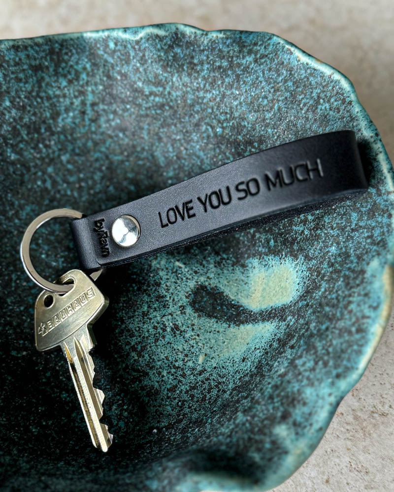 BOND Schlüsselanhänger aus schwarzem Leder mit persönlicher Gravur "Love you so much" und Schlüssel in türkiser Keramikschale