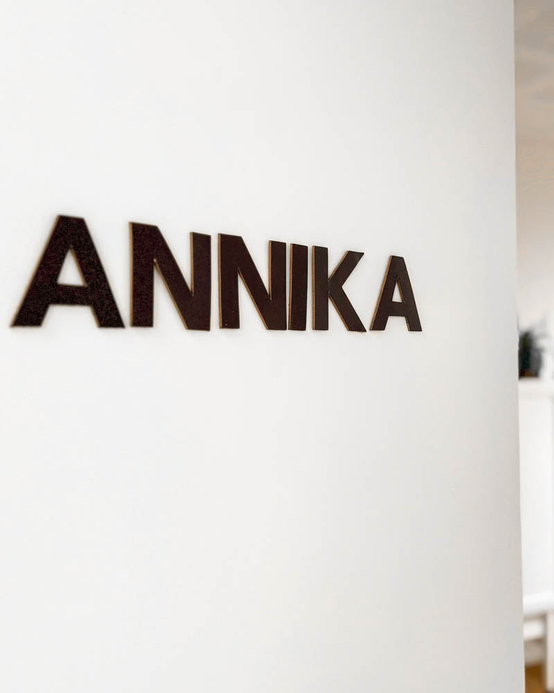 BOX Buchstaben aus dunkelbraunem Leder mit dem Namen "Annika" an weißer Wand montiert