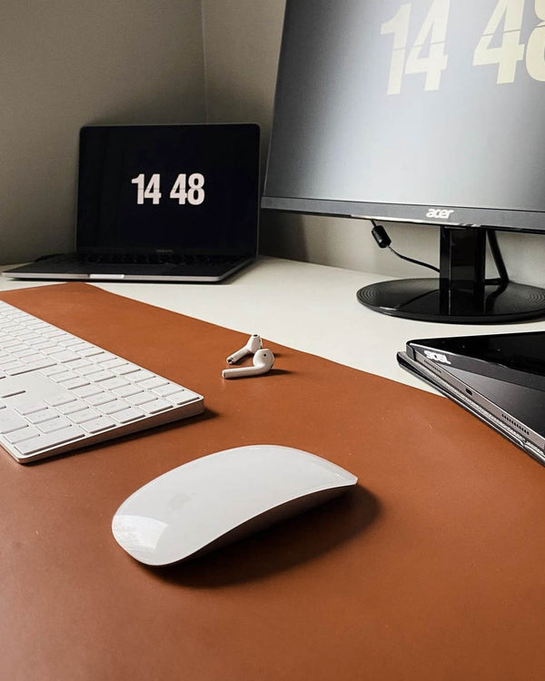 DESK Schreibtischunterlage aus cognacfarbenem Leder auf Schreibtisch mit Tastatur, Maus, Ohrhörern, Laptop und Monitor