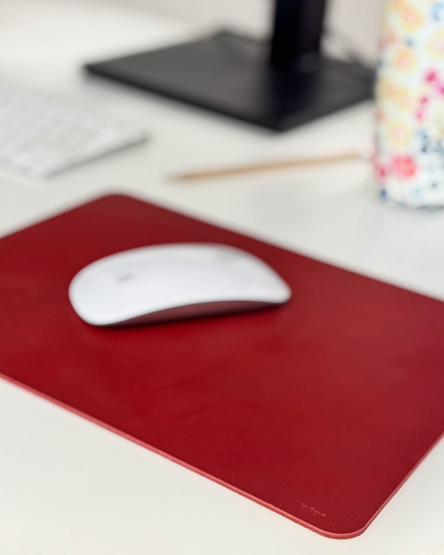 DOS Mauspad aus rotem Leder mit weißer Maus auf Schreibtisch mit Tastatur, Bleistift und geblümter Tasse