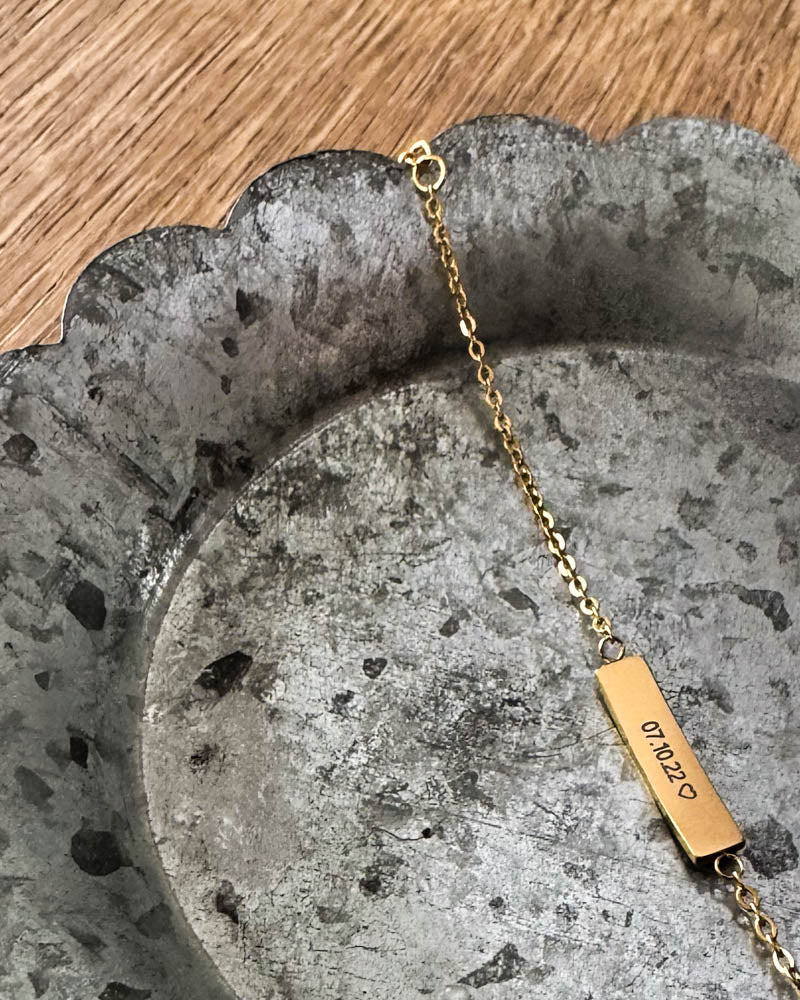 EVI Armband aus vergoldetem Edelstahl mit dem Datum "07.10.22" ♡ auf länglicher Platte graviert, auf Zinkschale liegend