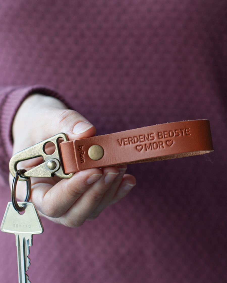 HOOK Schlüsselanhänger aus Cognac-Leder mit der Gravur "Verdens bedste mor" und Herzen, in der Hand gehalten mit Schlüssel