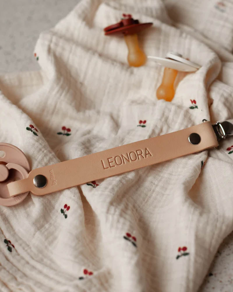 KODA Schnullerkette aus naturfarbenem Leder mit graviertem Namen "Leonora" auf Mulltuch mit Kirschen und zwei Schnullern