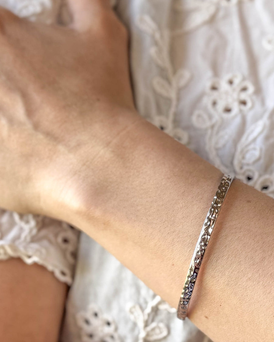 LUNA Armband aus silberfarbenem Edelstahl, gehämmerter Armreif am Handgelenk zu weißer Spitzenbluse getragen
