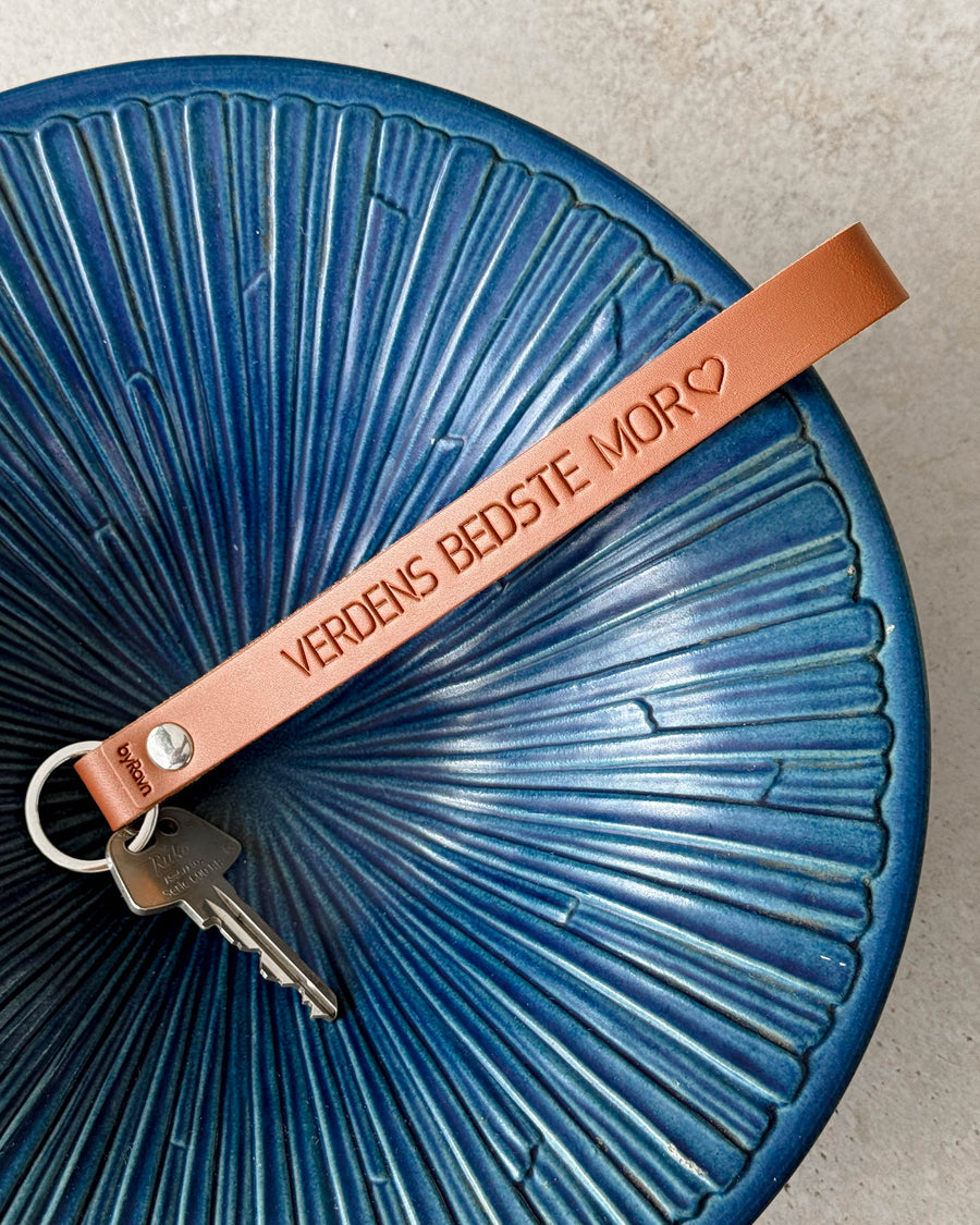 LUX Schlüsselanhänger aus Cognac-Leder mit der Gravur "Verdens bedste mor" ♡ und Schlüssel auf blauer geriffelter Keramikschale