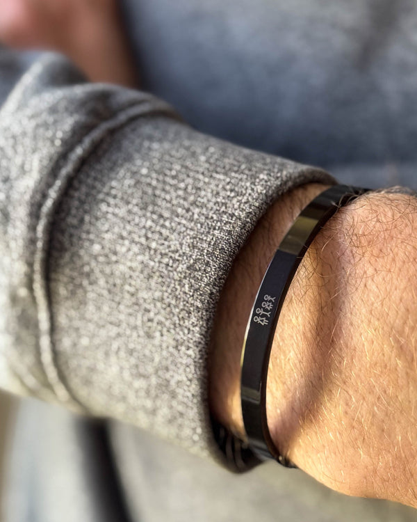 MARS STICK Armband aus schwarzem Edelstahl mit gravierter Streichholz-Familie, am Handgelenk zu grauem Strick getragen