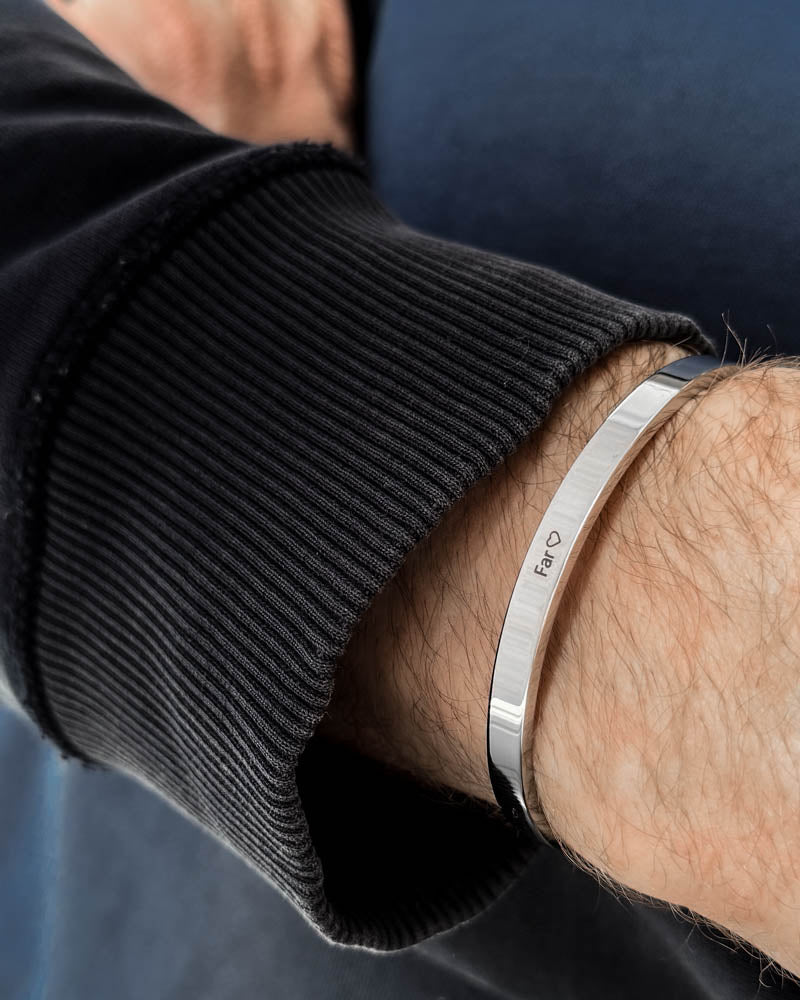 MARS Armband aus silberfarbenem Edelstahl mit der Gravur "Far" ♡ am Handgelenk, schwarzes Sweatshirt