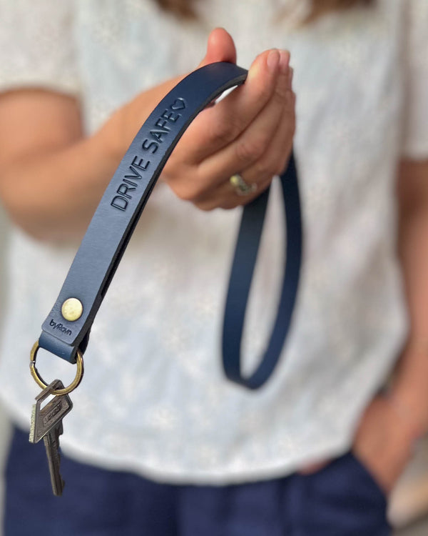 MAX Schlüsselanhänger aus dunkelblauem Leder als lange Schlaufe mit Messingniete und der Gravur "Drive safe" ♡, in der Hand gehalten mit Schlüssel