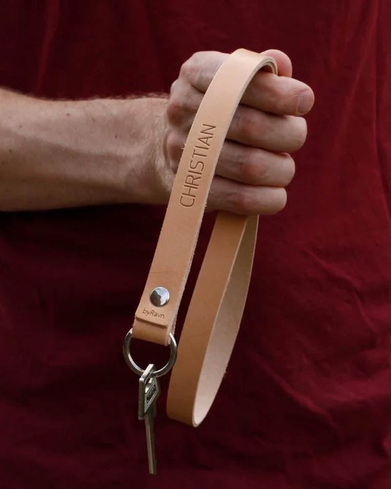 MAX Schlüsselanhänger aus naturfarbenem Leder als lange Schlaufe mit dem gravierten Namen "Christian", in der Hand gehalten mit Schlüssel