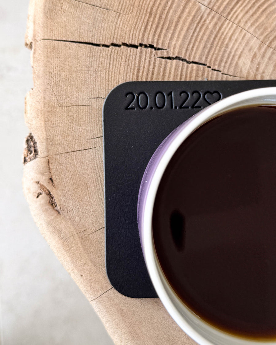 MOKKA quadratischer Untersetzer aus schwarzem Leder mit persönlicher Gravur "20.01.22" ♡ unter Kaffeetasse auf Holzscheibe
