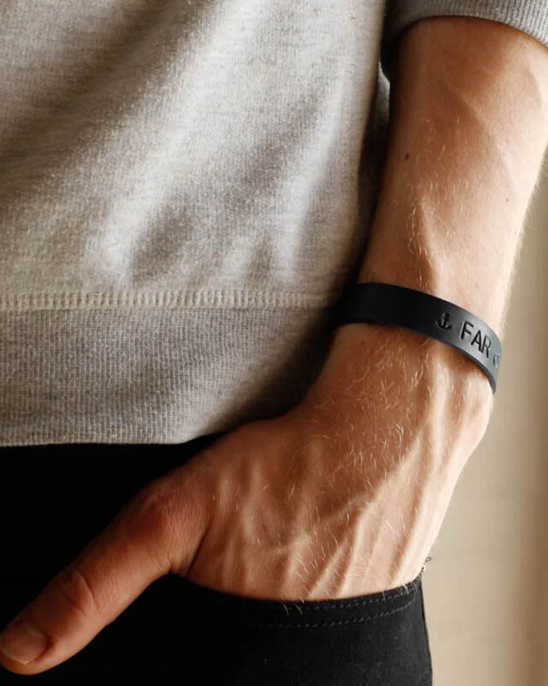 MONO Lederarmband in Schwarz mit Ankersymbol und der Gravur "Far" am Handgelenk, Hand in der Hosentasche