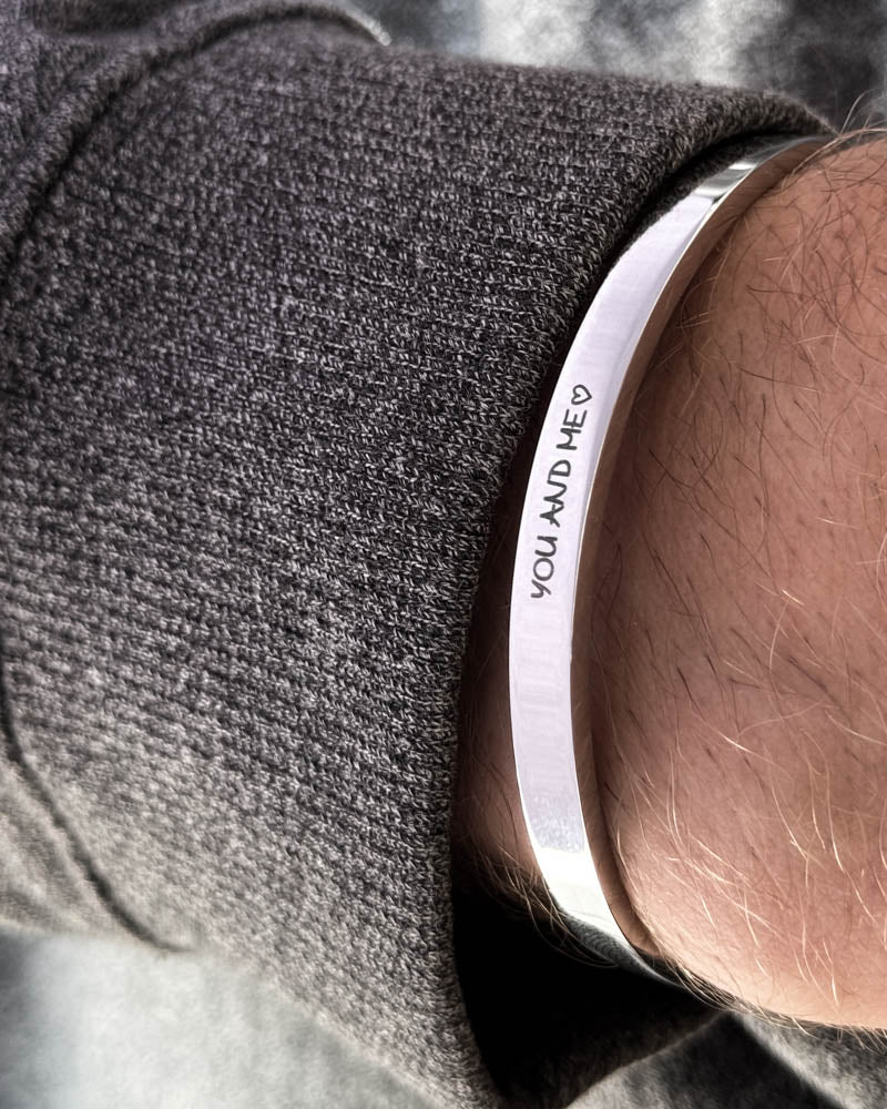 MARS SCRIPT Armband aus silberfarbenem Edelstahl, handschriftliche Gravur "You and me" ♡, zu dunkelgrauem Strick getragen