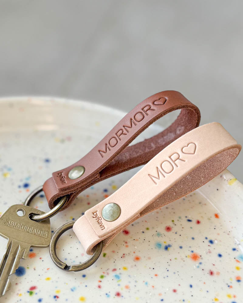 RAVN Schlüsselanhänger aus naturfarbenem und Cognac-Leder in gepunkteter Keramikschale mit den Gravuren "Mor" ♡ und "Mormor" ♡ sowie Schlüssel