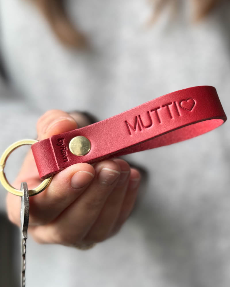 RAVN Schlüsselanhänger aus rotem Leder mit persönlicher Gravur "Mutti" ♡ und Messingniete, in der Hand gehalten mit Schlüssel
