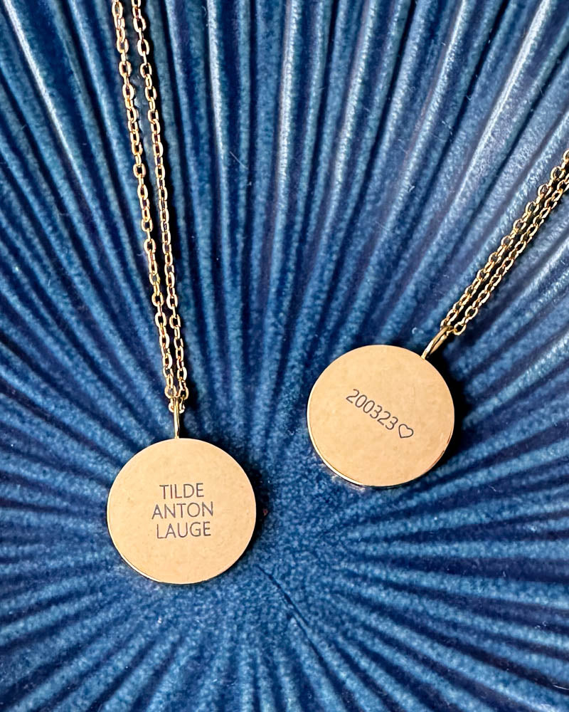 SIA QUOTE Namenskette aus vergoldetem Edelstahl, zwei Anhänger graviert mit "Tilde Anton Lauge" und "200323" ♡, auf blauer geriffelter Schale