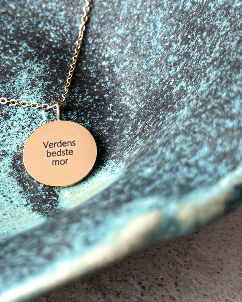 SIA QUOTE Halskette aus vergoldetem Edelstahl mit der Gravur "Verdens bedste mor" auf rundem Anhänger, in türkiser Keramikschale