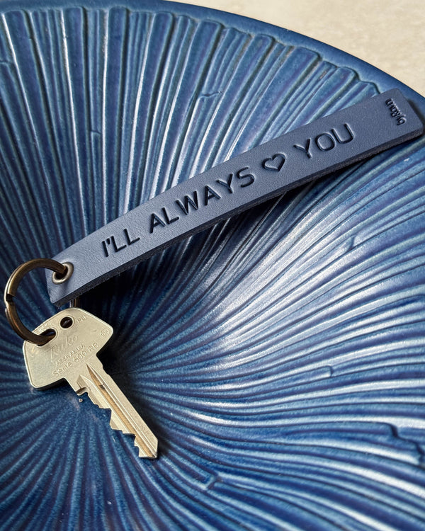 SOLO Large Schlüsselanhänger aus dunkelblauem Leder mit der Gravur "I'll always ♡ you" und Schlüssel in blauer geriffelter Keramikschale