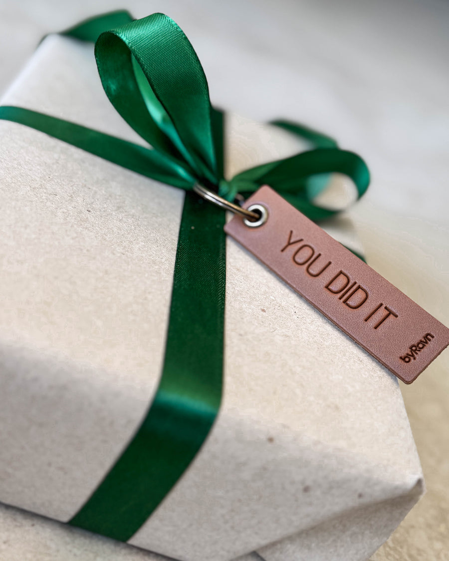 SOLO Small Schlüsselanhänger aus Leder in Cognac mit der Gravur "You did it" als Geschenkanhänger an Paket mit grünem Band