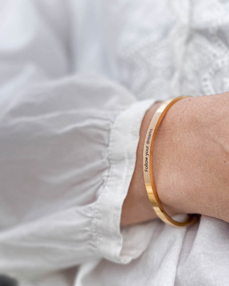 VENUS Armband aus vergoldetem Edelstahl mit der Gravur "Follow your dreams" zu weißer Bluse mit Puffärmeln