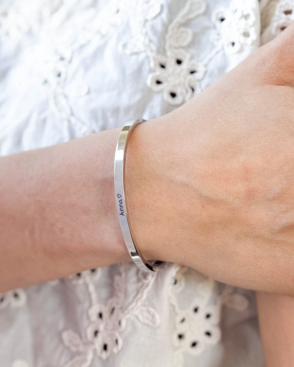 VENUS SCRIPT Armband aus silberfarbenem Edelstahl mit dem Namen "Anna" ♡ in Handschrift am Handgelenk, weiße bestickte Bluse