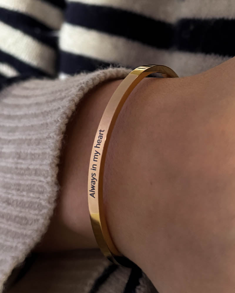 VENUS Armband aus vergoldetem Edelstahl mit der Gravur "Always in my heart" am Handgelenk, gestreifte Bluse