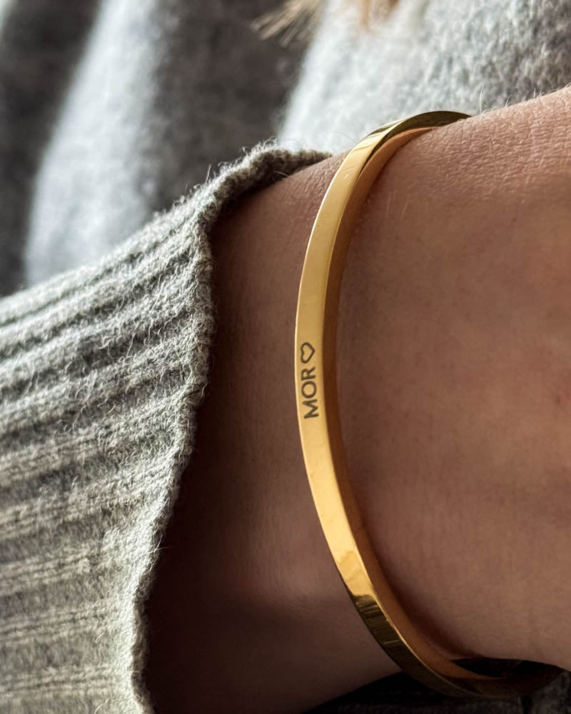 VENUS Armband aus vergoldetem Edelstahl mit persönlicher Gravur "Mor" ♡, getragen zu grauem Wollpullover