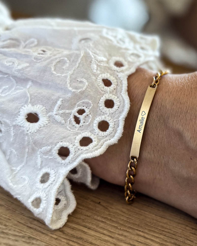 ZOE Namensarmband aus vergoldetem Edelstahl mit dem Namen "Amalie" ♡ graviert, am Handgelenk zu weißer Spitzenbluse getragen